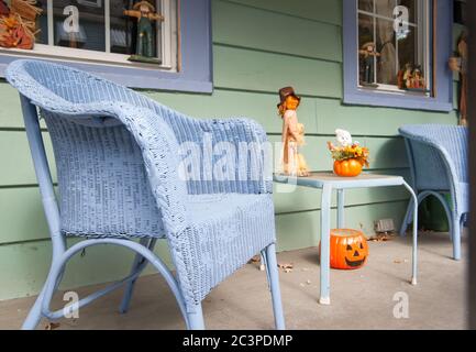 Malerische Veranda auf der Straße mit blauen Korbstühlen und halloween-Dekorationen. Stockfoto