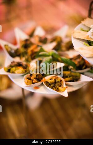 Vertikale Aufnahme der kleinen Teller der Catering-Vorspeisen auf a Fach unter den LEDs Stockfoto