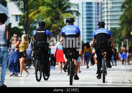 MIAMI - 17. MÄRZ 2019: Polizei auf dem Fahrrad fährt auf Ocean Drive, während sich junge Leute in South Beach für die jährlichen Frühlingsferien von der Schule versammeln. Stockfoto