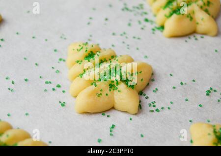 spritz Kekse in weihnachtsbaumformen auf Pergamentpapier mit grünen Zuckerstreuseln Stockfoto