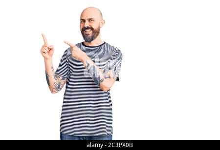 Junger, schöner Mann in lässiger Kleidung lächelnd und mit zwei Händen und Fingern zur Seite blickend auf die Kamera. Stockfoto