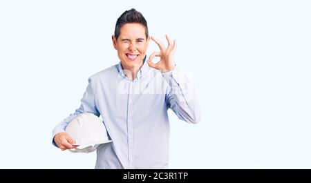 Junge Frau mit kurzen Haaren hält Architekt Hardhat tun ok Zeichen mit Fingern, lächelnd freundlich gestikulieren ausgezeichnete Symbol Stockfoto