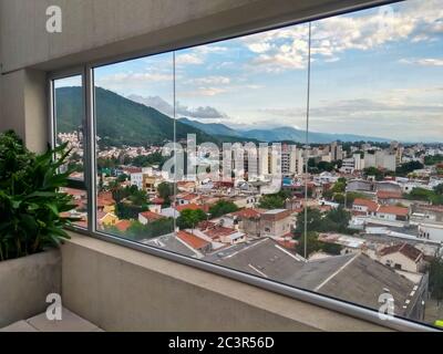 Blick auf Salta Stadt in Argentinien durch ein Fenster. Wolkiger Himmel. Hügel, Berge und die Stadt. Stockfoto