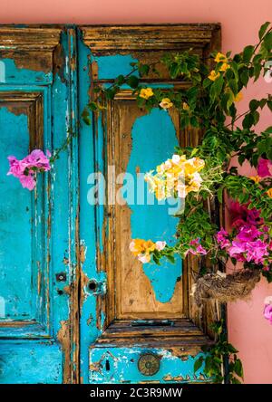 KATAKOLON, GRIECHENLAND - 04. Jun 2019: Eine alte rustikale Tür mit Rosen im Vordergrund. Stockfoto