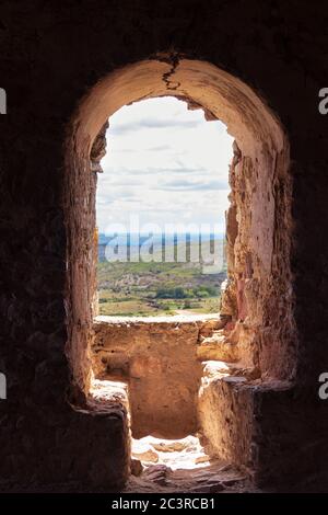 Vertikale Aufnahme eines alten Schlossfensters mit Aussicht Der nahen Hügel Stockfoto