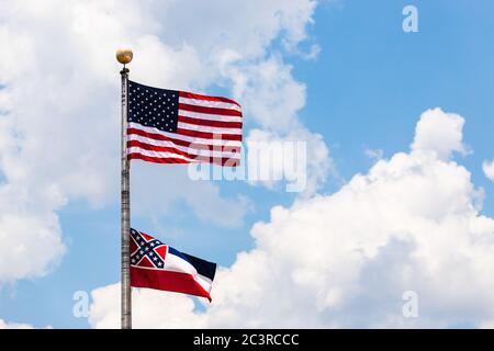 Flagge der Vereinigten Staaten und Staat Mississippi Flagge winkt im Wind auf Fahnenmast. Stockfoto
