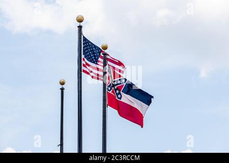 Fahnenmasten mit der Flagge der Vereinigten Staaten von Amerika und der Flagge des Staates Mississippi, die im Wind gegen den blauen Himmel schwenkt. Stockfoto