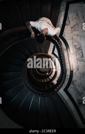 Vertikale Aufnahme eines jungen Mannes, der nach unten schaut Zu einer runden Treppe Stockfoto