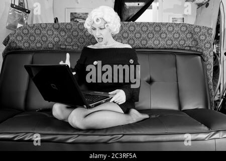 Moderne nehmen Marilyn, Retro-Stile, Vintage-Stile, Periode Stile. Marilyn Monroe Satire, frustriert mit ihrem Laptop in ihrem chaotischen Haus Stockfoto