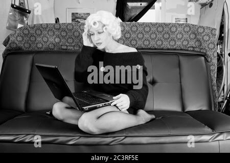 Moderne nehmen Marilyn, Retro-Stile, Vintage-Stile, Periode Stile. Marilyn Monroe Satire, frustriert mit ihrem Laptop in ihrem chaotischen Haus Stockfoto