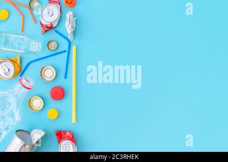 Recycelbarer verschiedenfarbiger Müll bestehend aus Papier, Glas, Metall, Kunststoff auf blauem Hintergrund. Abfalltrennungskonzept. Flatlay, Kopierplatz. Stockfoto