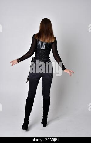 Portrait von Brünette Mädchen trägt schwarzen Leder Catsuit. In voller Länge stehende Pose, isoliert vor einem Studio-Hintergrund. Stockfoto