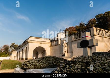 polnisches Grab mit Kreuz neben Bogengalerie mit Skulptur auf dem Friedhof Lischakiw in der ukraine Stockfoto