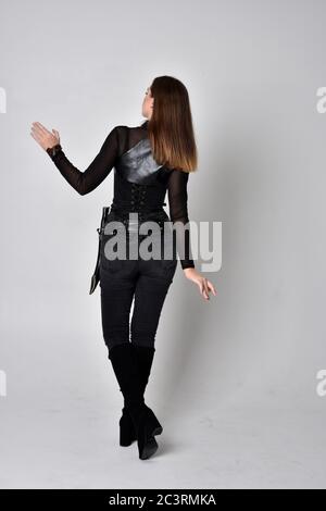 Portrait von Brünette Mädchen trägt schwarzen Leder Catsuit. In voller Länge stehende Pose, isoliert vor einem Studio-Hintergrund. Stockfoto