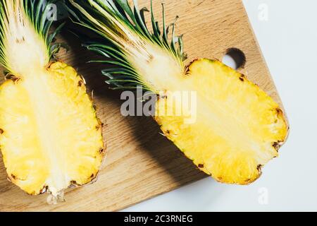 Draufsicht auf saftige Ananas Hälften auf Holz Schneidebrett auf weißem Hintergrund Stockfoto