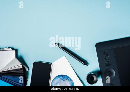 Draufsicht auf Smartphone, Farbfelder mit Grafik-Tablet und Aquarell-Zeichnung auf blauem Hintergrund Stockfoto