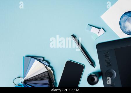 Draufsicht auf Farbfelder, Smartphone in der Nähe von Grafik-Tablet und Aquarell Zeichnung auf blauer Oberfläche Stockfoto