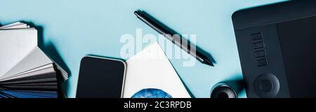 Panorama-Aufnahme von Grafik-Tablet, Smartphone und Farbproben auf blauem Hintergrund Stockfoto