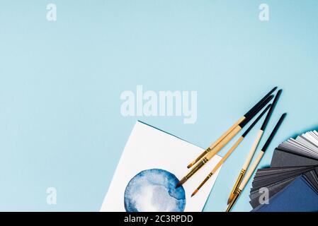 Draufsicht auf Pinsel auf Aquarellmalerei und Farbmuster auf blauem Hintergrund Stockfoto