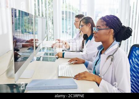 Gruppe von jungen Ärzten arbeiten an Computern, Analyse von Röntgenstrahlen und medizinischen Tests Ergebnisse von Patienten Stockfoto