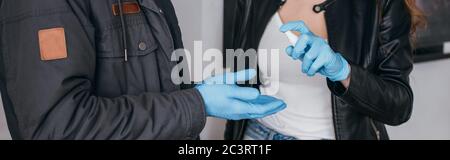 Teilansicht des Paares in medizinischen Masken und Latexhandschuhe mit antiseptischem Spray, Panoramaaufnahme Stockfoto