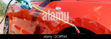Beschnittene Ansicht des Spezialisten für einheitliche Reinigung Auto mit Desinfektionsmittel in Sprühbeutel während covid-19 Pandemie, horizontale Ernte Stockfoto