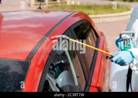 Beschnittene Ansicht des Spezialisten in Gefahrgut-Reinigung Auto mit Desinfektionsmittel Spray während Coronavirus Pandemie Stockfoto