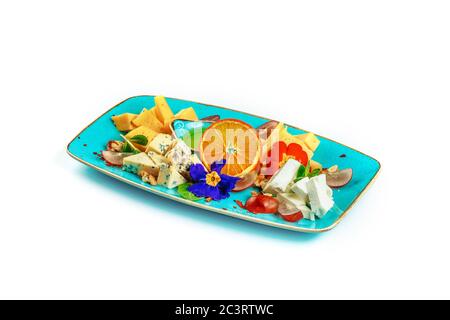 Verschiedene Arten von köstlichen Käse in Scheiben geschnitten liegen in blau auf einem weißen Hintergrund. Serviert mit Honig. Dekoriert mit frischen Blumen. Isoliert Stockfoto