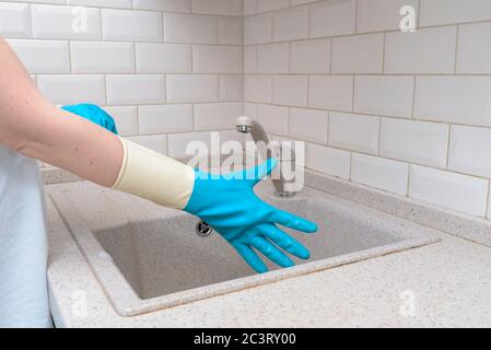 Frau Hand holding gelben Schwamm und waschen Untertasse mit gewaschenem Geschirr im Hintergrund Stockfoto
