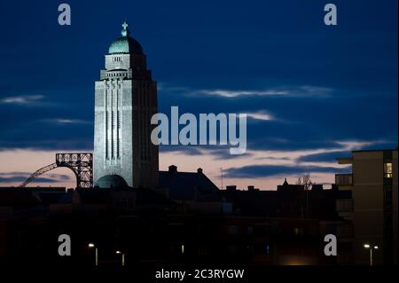 Eine Silhouette eines Wohnviertels von Kallio in der Nacht mit beleuchteten Kirchturm gegen Wolken. Stockfoto