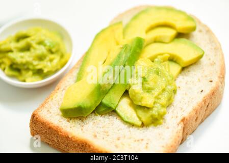 Avocado in Scheiben geschnitten und Avocado Toast auf weißem Teller Hintergrund Früchte gesunde Ernährung Konzept / Avocado Dip püriert Stockfoto