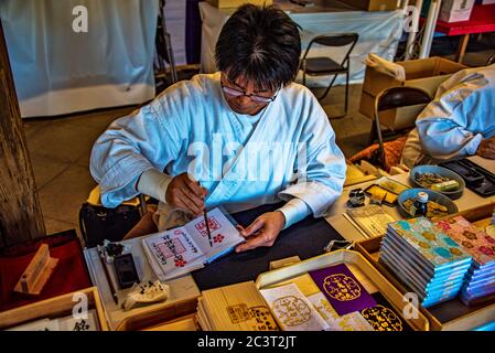 Mönch schreiben Goshuin Kitano Tenmangu shinto-Schrein, Kyoto, Japan Stockfoto