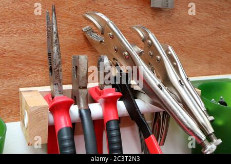 Reihe von verschiedenen Zangen und Griffe auf hausgemachten Rack in einer Werkstatt Stockfoto