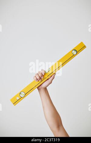 Hand des Bauarbeiters, der Wasserwaage zeigt, isoliert auf grau Stockfoto