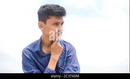 Portrait von schönen jungen Teenager-Mann in tiefen Gedanken über seine Zukunft auf Himmel Hintergrund. Stockfoto