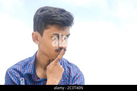 Portrait von schönen jungen Teenager-Mann in tiefen Gedanken über seine Zukunft auf Himmel Hintergrund. Stockfoto