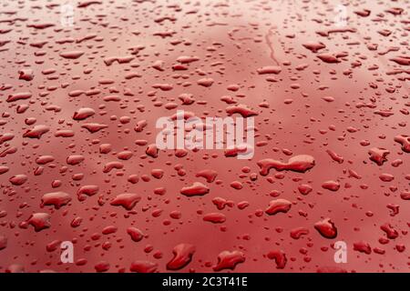 Wassertropfen auf einer roten Oberfläche Stockfoto