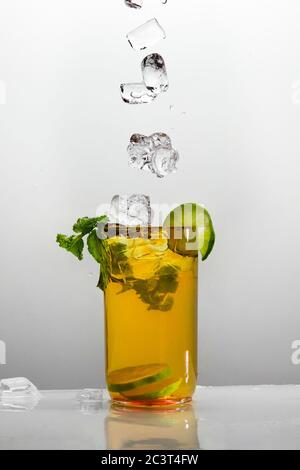 Glas Zitronen-Eistee mit Pfefferminzblättern und Eiswürfeln. Isoliert auf weißem Hintergrund. Stockfoto