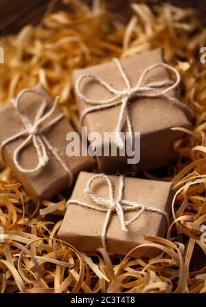 Rustikale kleine Geschenkboxen liegen in Naturholzspäne. Stockfoto