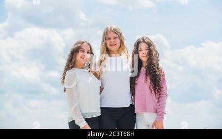 Drei Mädchen auf Himmel Hintergrund. Konzept der weiblichen Freundschaft. schwesternschaft und Familie. Beste Freunde zusammen in der Schule. Zurück zur Schule. Glückliche Kindheit. Fröhliche kleine Kinder. Stockfoto