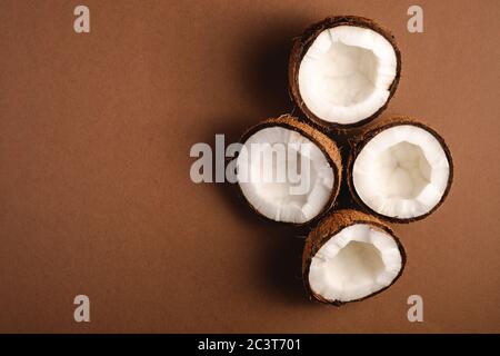 Kokosnussfrüchte auf braunem, einfarbigem Hintergrund, abstraktes, tropisches Konzept, Ansicht von oben, Kopierraum Stockfoto