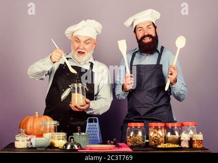 Genießen zusammen kochen. Halloween Kürbis Rezept. Getreide, Gewürze. Professionelle restaurant Kochen. reifen älteren bärtigen Männern in der Küche. Koch Männer kochen. Freundliche Männer bereiten Essen. Stockfoto