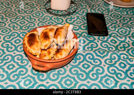 Handgemachte Keramik-Topf mit Simil einheimischen Töpferwaren mit frischen hausgemachten Empanadas (detaillierte Nahaufnahme; selektive Fokus) Stockfoto