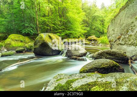 Erstaunliche Waldnatur, Fluss mit Felsen in wunderbaren Frühling Sommer Sonnenlicht. Natur Wunderland kleiner Wasserfall in grünen Wald üppige Landschaft Stockfoto