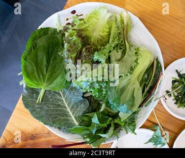 Gemüse-Set für ssam. Reis und Gewürze in Blätter von Salat, Kohl, Sesam oder anderen Grüns eingewickelt. Stockfoto