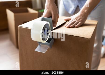 Nahaufnahme Mann versiegeln Karton mit Klebeband Stockfoto