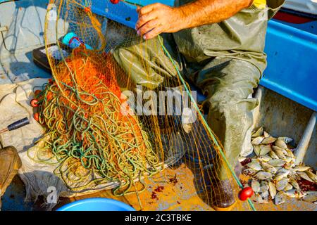 Fisher in Gummihosen und Boot sitzen in seinem Boot und stapeln Angelnetz  für Angeln auf offener See Stockfotografie - Alamy