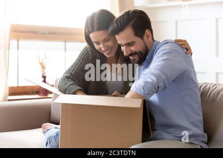 Neugierige junge Paar Auspacken Karton Paket zusammen Stockfoto