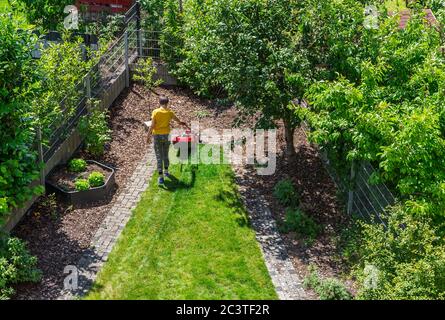 Junge Schneiden des Grases mit Elektromäher. Gartenkonzept. Draufsicht Stockfoto