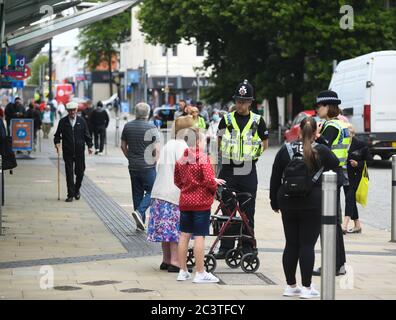 Swansea, Wales, Großbritannien. Juni 2020. Polizeibeamte unterhalten sich mit Käufern, während in Swansea, Südwales, Geschäfte eröffnet werden, die nicht unbedingt notwendig sind, da Geschäfte in ganz Wales zum ersten Mal seit Einführung von Beschränkungen durch das Coronavirus ihre Türen für Käufer öffnen. Es ist eine Woche später, seit nicht-wesentliche Geschäfte in England eröffnet. Kredit : Robert Melen/Alamy Live Nachrichten Stockfoto